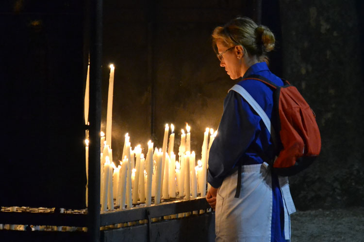 A woman lighting a candle at Lourdes (Photo: WYM)